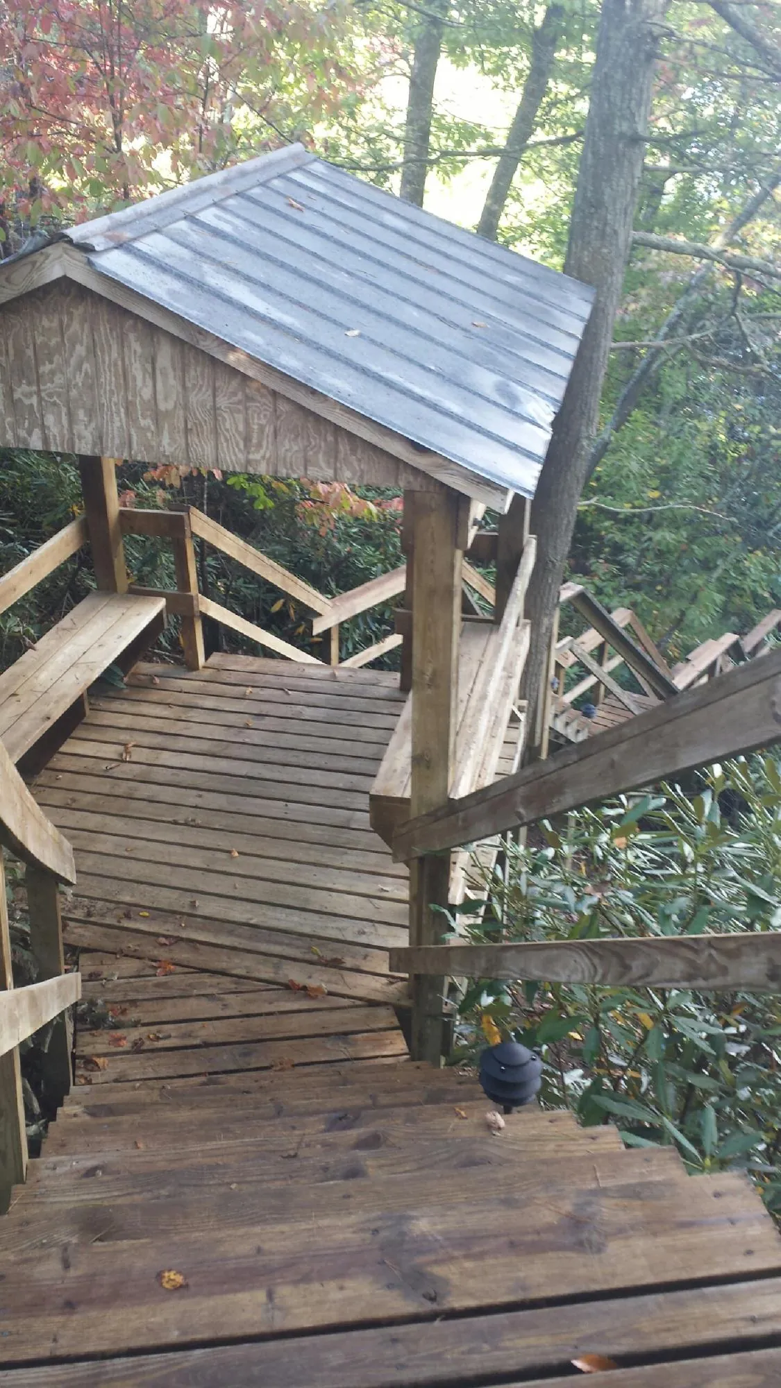 Metal roofed shelter over wooden steps on a wooded walkway — Skylight Repair & Installation work by our crew in Stanton
