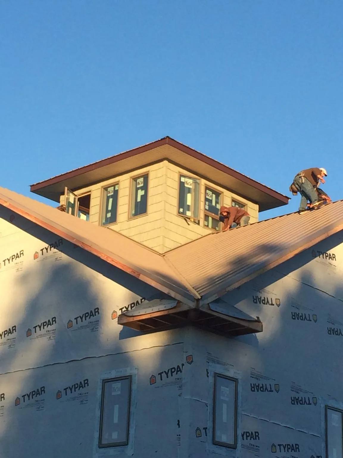 Roofers working around a rooftop cupola on a new metal roof at sunset — Roof Waterproofing in Stanton by Roofing Brothers
